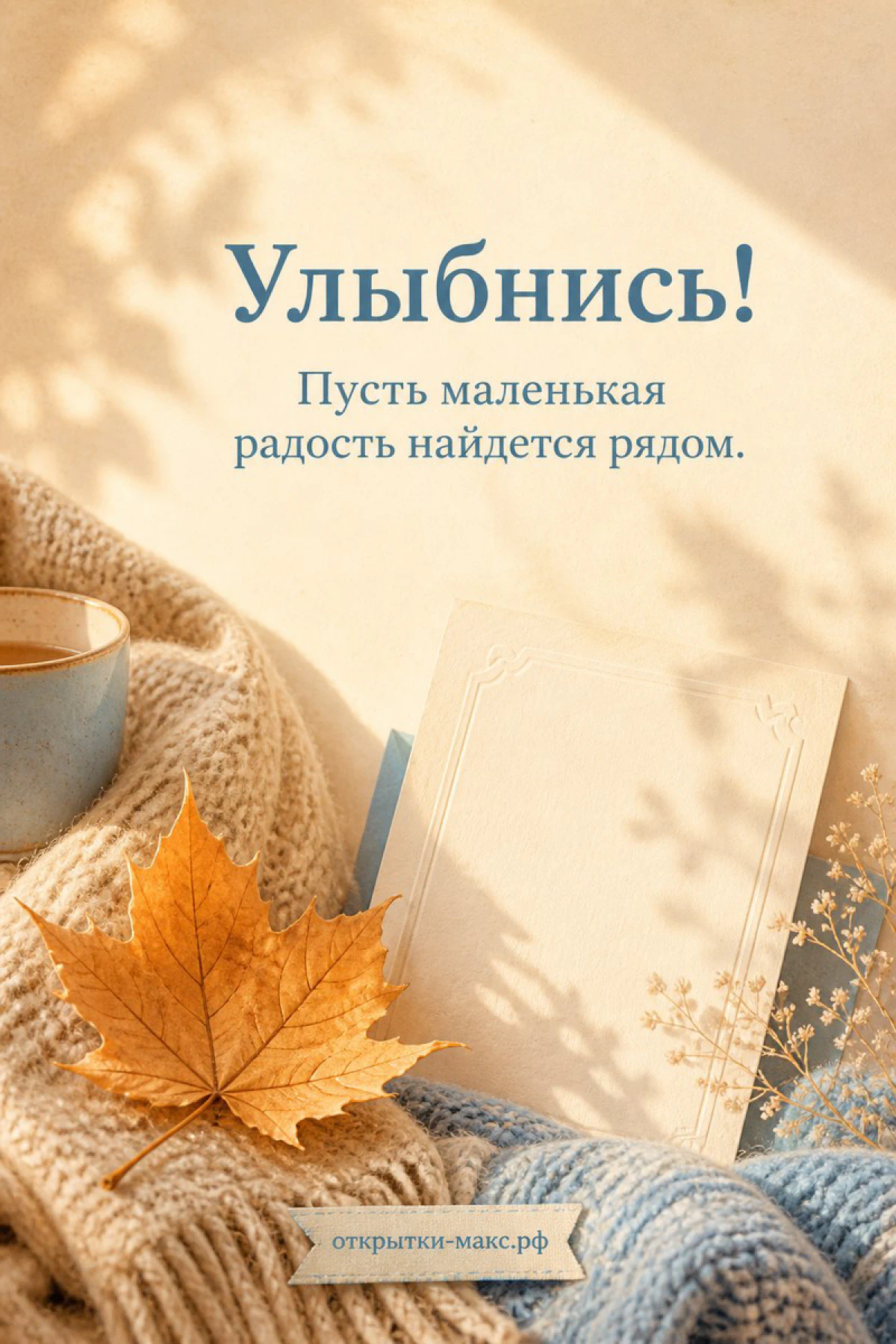 Оранжевый кленовый лист на бежевом вязаном пледе рядом с кружкой кофе и книгой, надпись «Улыбнись»